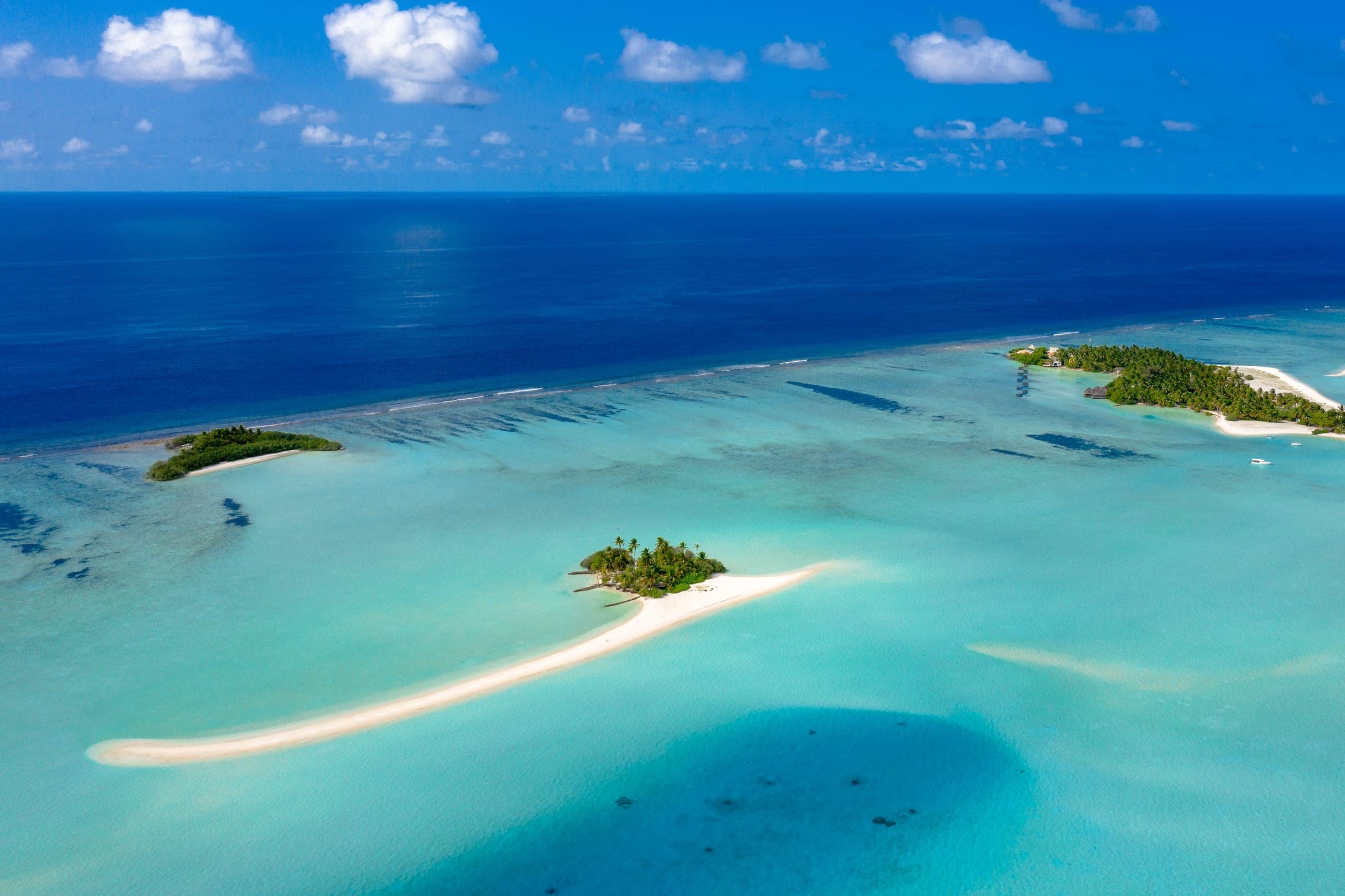 Aerial view of small Maldivian islands with white sandbars, a reef edge and a turquoise lagoon